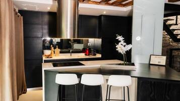 Une cuisine moderne dotée d’un îlot central, de tabourets de bar et d’une hotte de cuisine en acier inoxydable.