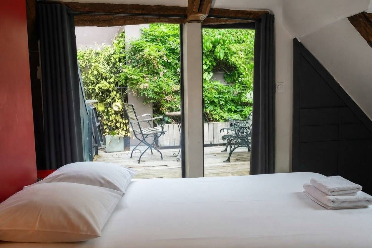 A bedroom with a bed, a view of the outside, and a window.