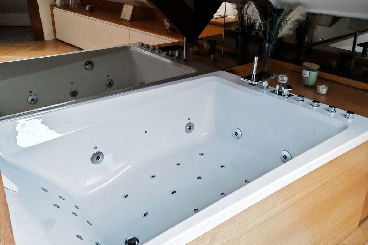 A large, rectangular bathtub in a room with wooden beams and a skylight.
