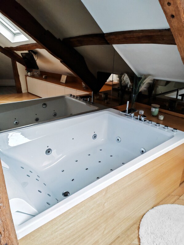 A large, rectangular bathtub in a room with wooden beams and a skylight. - villa raspail (Ivry-sur-Seine)