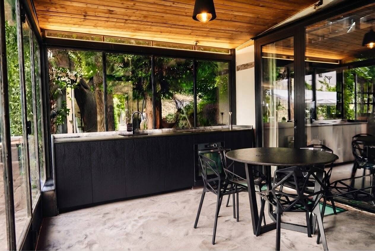 A modern kitchen with a built-in island, black cabinetry, and a round dining table with chairs.