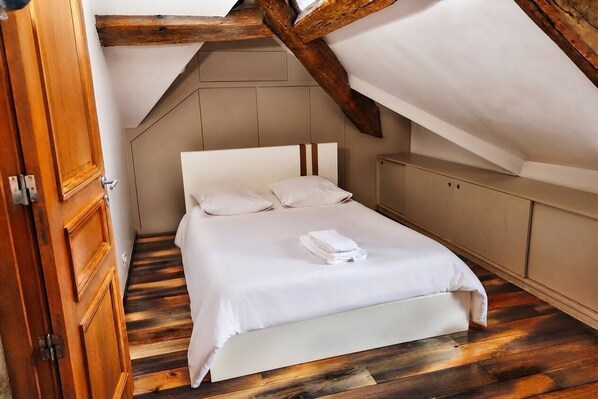 A bedroom with a wooden ceiling, a bed with white bedding, and a wooden floor. - villa raspail (Ivry-sur-Seine)