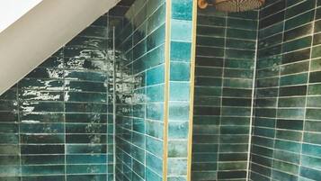 A shower with blue-tiled walls and a gold showerhead.