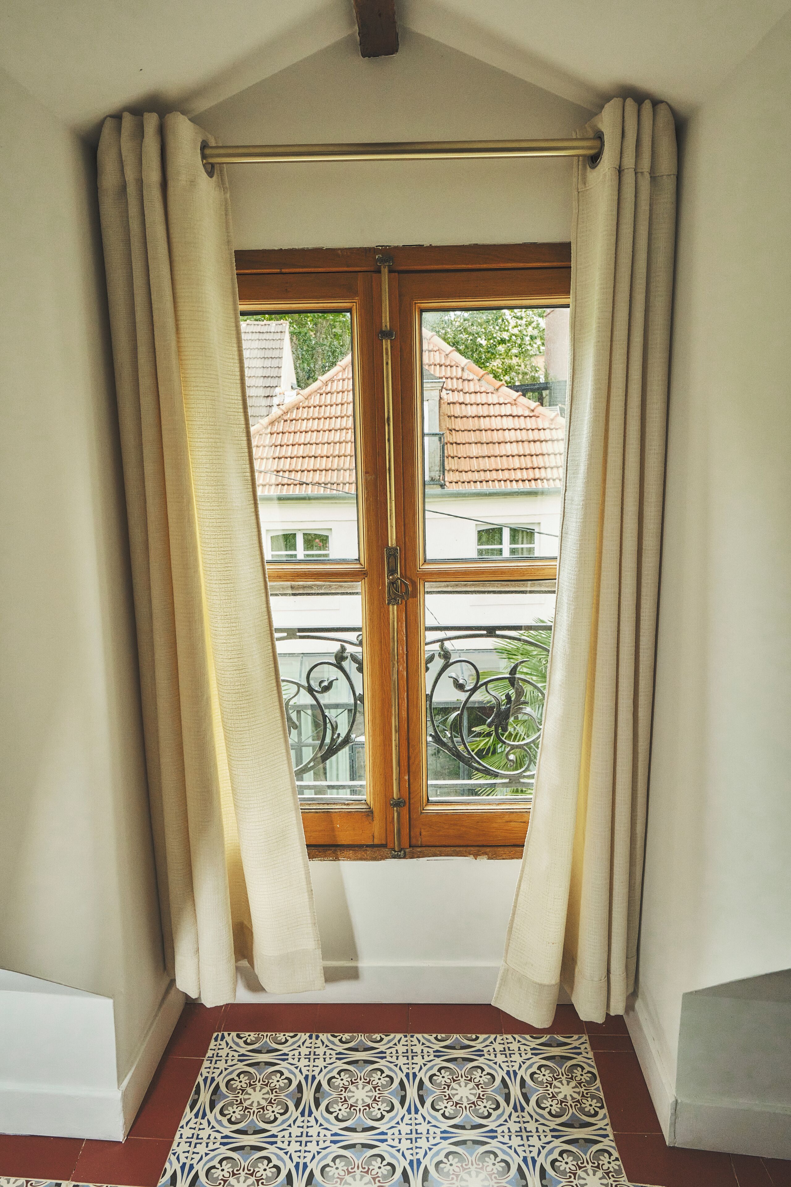 Een kamer met een houten deur, beige gordijnen en een kamerkleed met dessin.