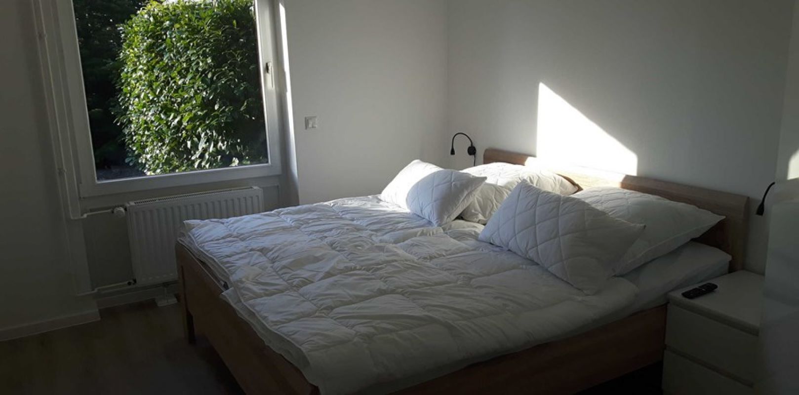 Una camera da letto con un letto, un comodino, una finestra e un termosifone.