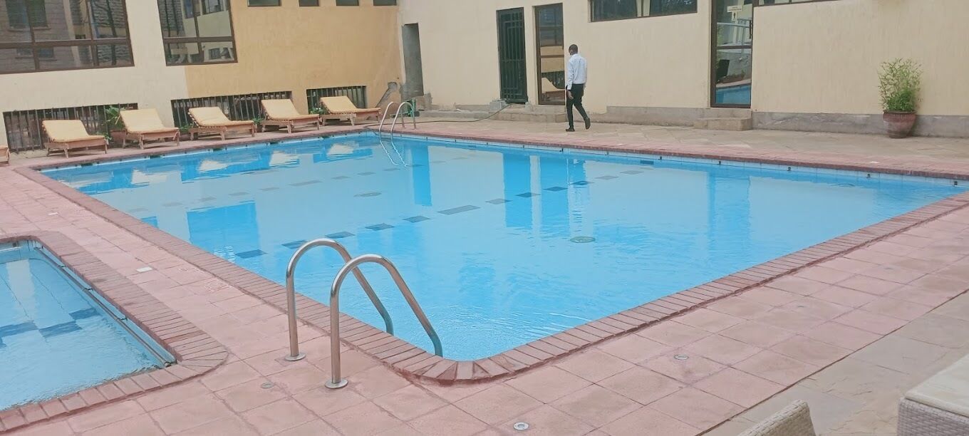 A swimming pool with lounge chairs and a person walking.
