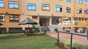 Un patio con zona de comedor, mobiliario exterior y una escalera que conduce a la entrada del edificio.