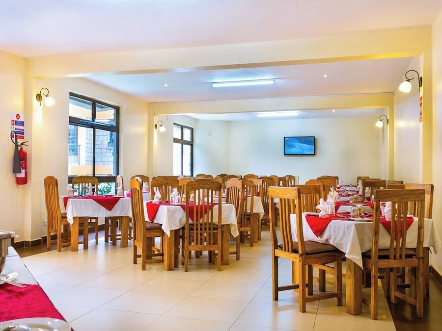 A dining area with multiple tables and chairs, a fire extinguisher on the wall, and a television mounted on the wall.