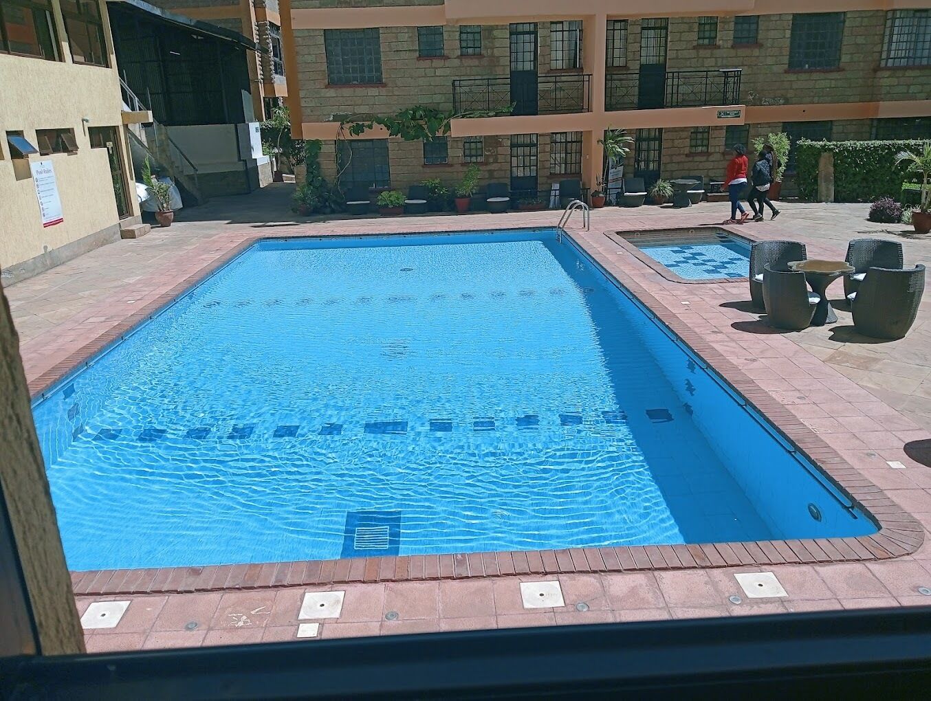 Una piscina rectangular con borde de azulejos y decoración de ladrillo.