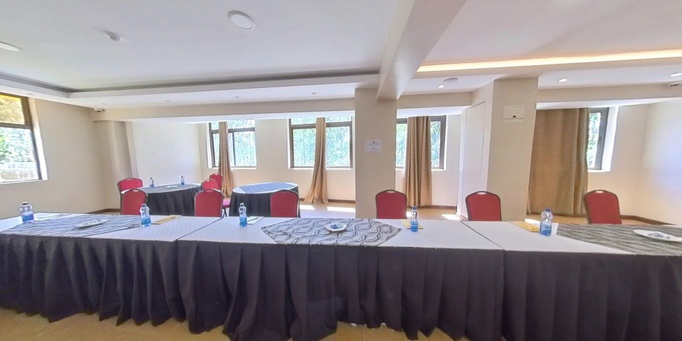 Una sala conferenze con un lungo tavolo, sedie rosse e una tovaglia nera.