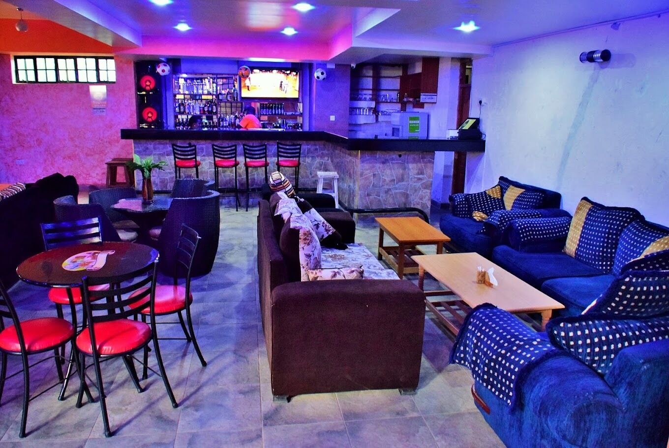 A bar area with a counter, seating, and a TV screen.
