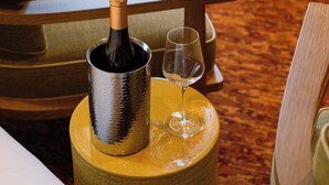 A room with a wooden chair, a small round table, a bottle of wine, and a wine glass. - Confidential Room 5, a Stone's Throw From the Louvre (Paris)