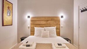 A hotel room with a wooden headboard, white bedding, two bedside tables, and a painting on the wall. - Wonderful Apartment Center of Paris-montorgueil (Paris)
