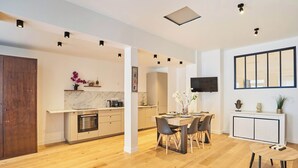 A modern kitchen with a marble countertop, wooden cabinets, and a dining area with a table and chairs. - Wonderful Apartment Center of Paris-montorgueil (Paris)