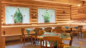 A wooden cabin interior with multiple dining tables, chairs, and large windows with curtains. - Room 'Cazzuffi Rododendro' with Mountain View, Private Terrace and Wi-Fi (Cogolo di Peio)