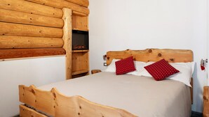 A wooden cabin-style room with a bed, a wooden headboard, and a built-in shelf with a television. - Room 'Cazzuffi Rododendro' with Mountain View, Private Terrace and Wi-Fi (Cogolo di Peio)