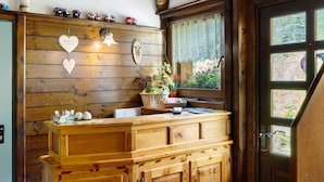 A wooden reception desk with a window, decorative wall items, and a door. - Room 'Cazzuffi Rododendro' with Mountain View, Private Terrace and Wi-Fi (Cogolo di Peio)