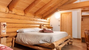 A log cabin-style bedroom with a wooden bed frame, a bedside table, and a wooden door. - Room 'Cazzuffi Salvia' with Mountain View, Shared Garden and Wi-Fi (Cogolo di Peio)