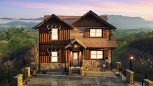 A two-story wooden house with a stone foundation, large windows, and a stone staircase leading to the entrance. - Fantastic View|Theater|Indr Pool|Pool Table|HotTub (Sevierville)