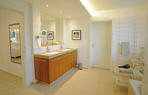 Een moderne badkamer met een houten wastafelmeubel, een grote spiegel, een wastafel en een handdoekrek.