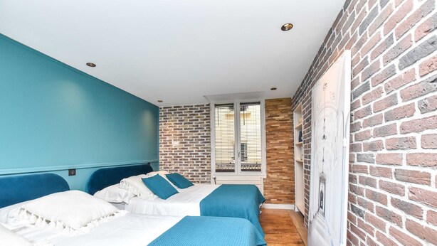 A room with two beds, a brick wall, and a window with blinds. - Charming 3BR Apt- Montorgueil / Republique (Paris)