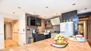 A modern kitchen with a brick backsplash, stainless steel appliances, and a wooden countertop. - Charming 3BR Apt- Montorgueil / Republique (Paris)