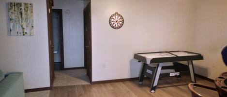 A room with a dartboard, a pool table, and a door leading to another room.