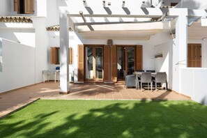Un'area patio con tavolo e sedie, una zona salotto coperta e un'uscita che dà su un ambiente interno.