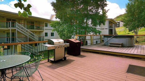 A deck with a grill, a table with chairs, and a trash can. - Oak at Outrun, brand new remodel, fireplace! (Mt. Crested Butte)