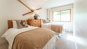 A bedroom with two beds, a wooden headboard, a lamp, and a window. - Oak at Outrun, brand new remodel, fireplace! (Mt. Crested Butte)