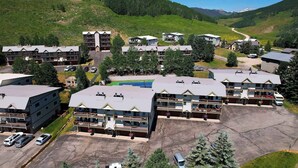 A hotel complex with multiple buildings, parking areas, and a mountainous backdrop. - Oak at Outrun, brand new remodel, fireplace! (Mt. Crested Butte)