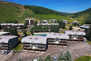 A hotel complex with multiple buildings, parking areas, and a mountainous backdrop.