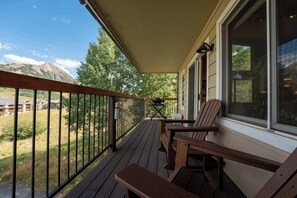A wooden deck with a view of mountains and a building in the distance.