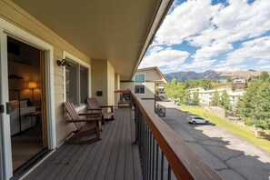 A wooden deck with outdoor seating, a view of a mountain range, and a parking area. - Oak at Outrun, brand new remodel, fireplace! (Mt. Crested Butte)