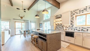 A modern kitchen with a central island, wooden cabinets, and pendant lighting. - Oak at Outrun, brand new remodel, fireplace! (Mt. Crested Butte)