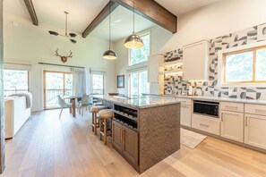 A modern kitchen with a central island, wooden cabinets, and pendant lighting. - Oak at Outrun, brand new remodel, fireplace! (Mt. Crested Butte)