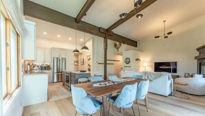 A spacious kitchen with modern appliances, a dining area with a wooden table and blue chairs, and a living area with a sofa and TV. - Oak at Outrun, brand new remodel, fireplace! (Mt. Crested Butte)