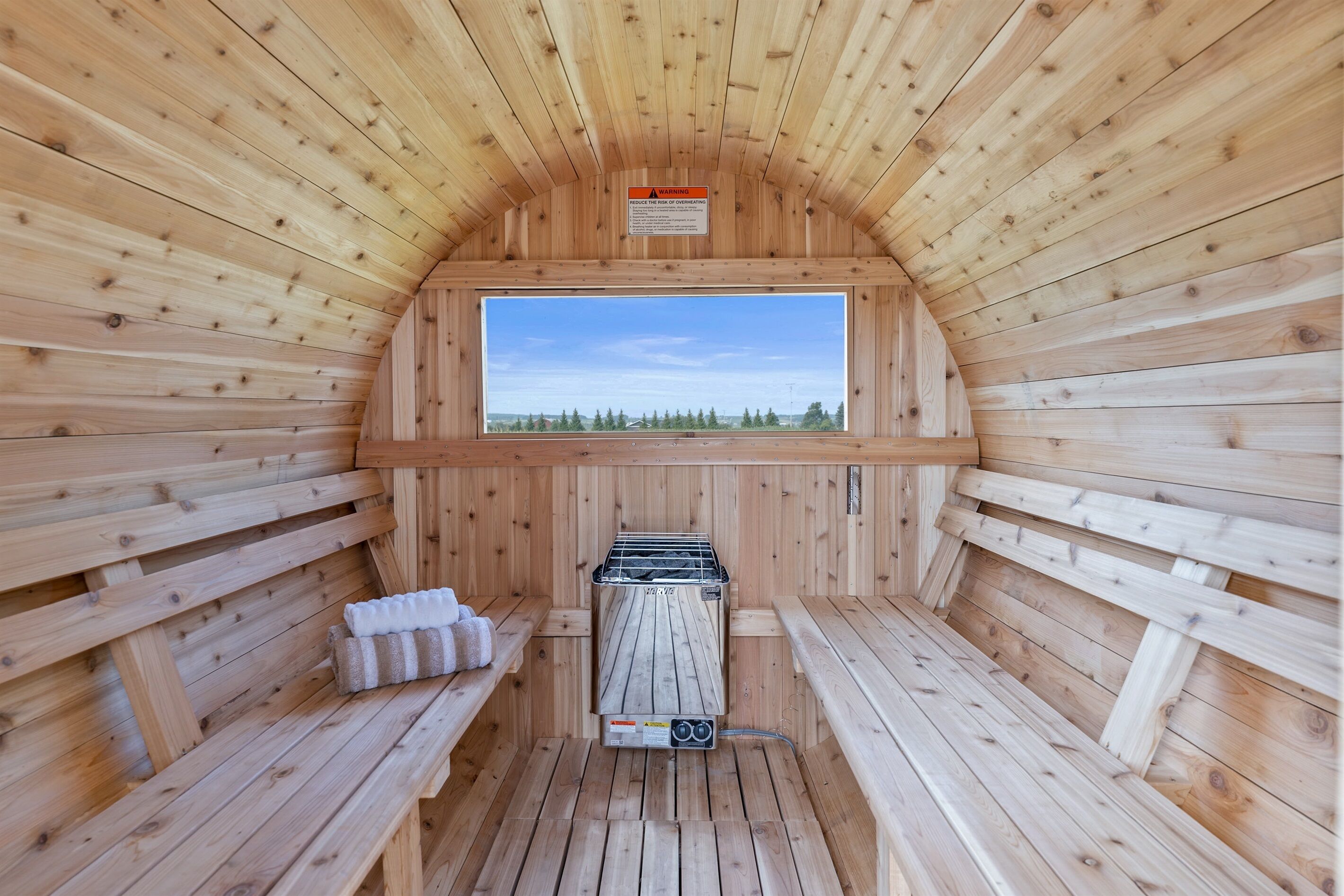 A sauna with wooden walls, a bench, a bench with towels, and a sauna heater.