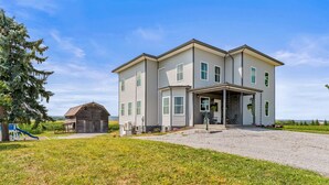 A two-story house with a front porch, a small shed, and a playground. - Secluded Wine Retreat | Game Room | Sauna/Firepit (Penn Yan)