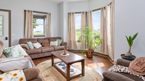 A living room with a brown sofa, a coffee table, and a potted plant. - Secluded Wine Retreat | Game Room | Sauna/Firepit (Penn Yan)
