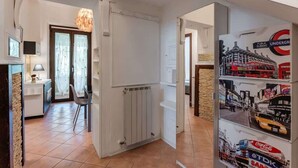 A hallway with a radiator, a door leading to another room, and a wall with posters.