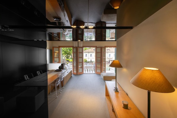 A modern kitchen with a dining area, a staircase, and a view of the street.