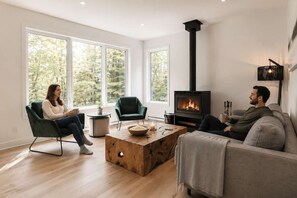 A modern living room with a fireplace, large windows, and a cozy seating arrangement. - BOREA Chalet | Spa, Golf & Outdoor Activities (Mont-Blanc)