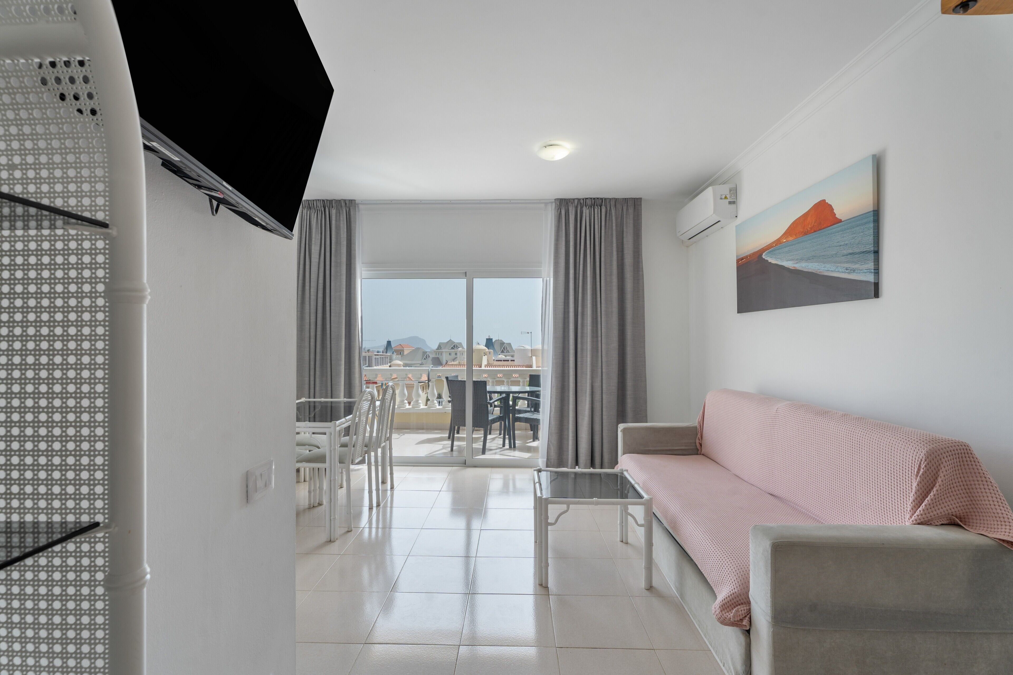 Una sala de estar moderna con un sofá, una mesa de centro de vidrio y un comedor con sillas y una mesa.