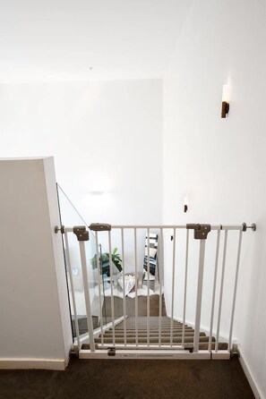 Een trap met een witte balustrade, een deur aan de linkerkant en een lamp aan de muur.