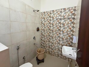 Et badeværelse med brusebad, toilet, vask og en dekorativ flisemur.