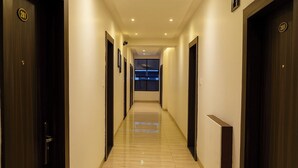 A hotel hallway with doors numbered 201, a polished floor, and a view of a room at the end. - Hotel Shubhshree (Indore)