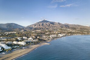 Un pueblo costero con una montaña destacada, playa y edificios residenciales.