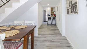 A modern kitchen with stainless steel appliances, a dining area with a wooden table and chairs, and a staircase leading to another level. - Marbella 22 Beach&Comfort just steps from the sea (Marbella)
