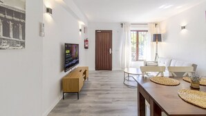 A modern living room with a wooden TV stand, a dining table with woven placemats, and a sofa. - Marbella 22 Beach&Comfort just steps from the sea (Marbella)
